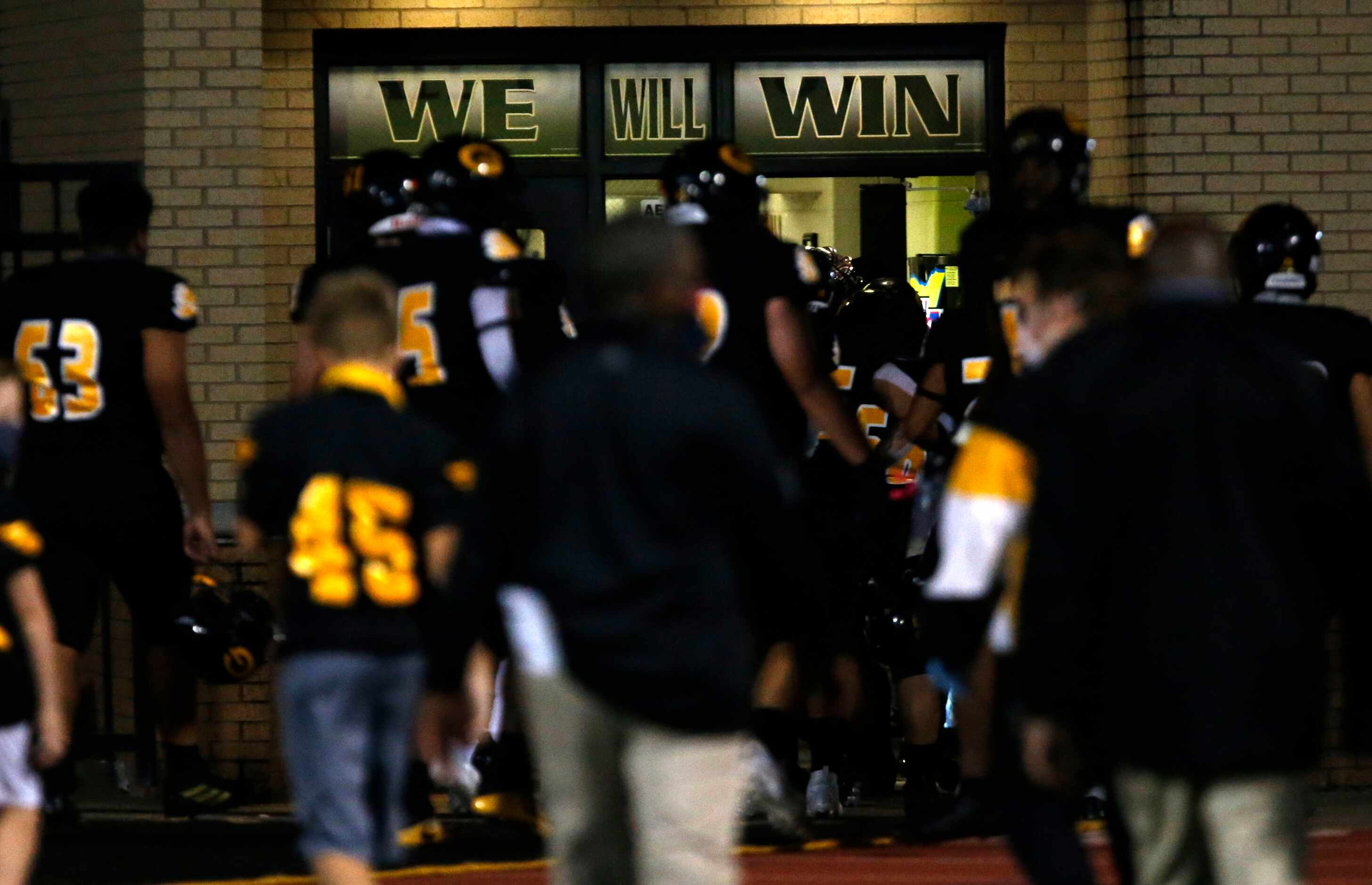 The Garland Owls head to the locker room during half-time, under a window that reads “WE...
