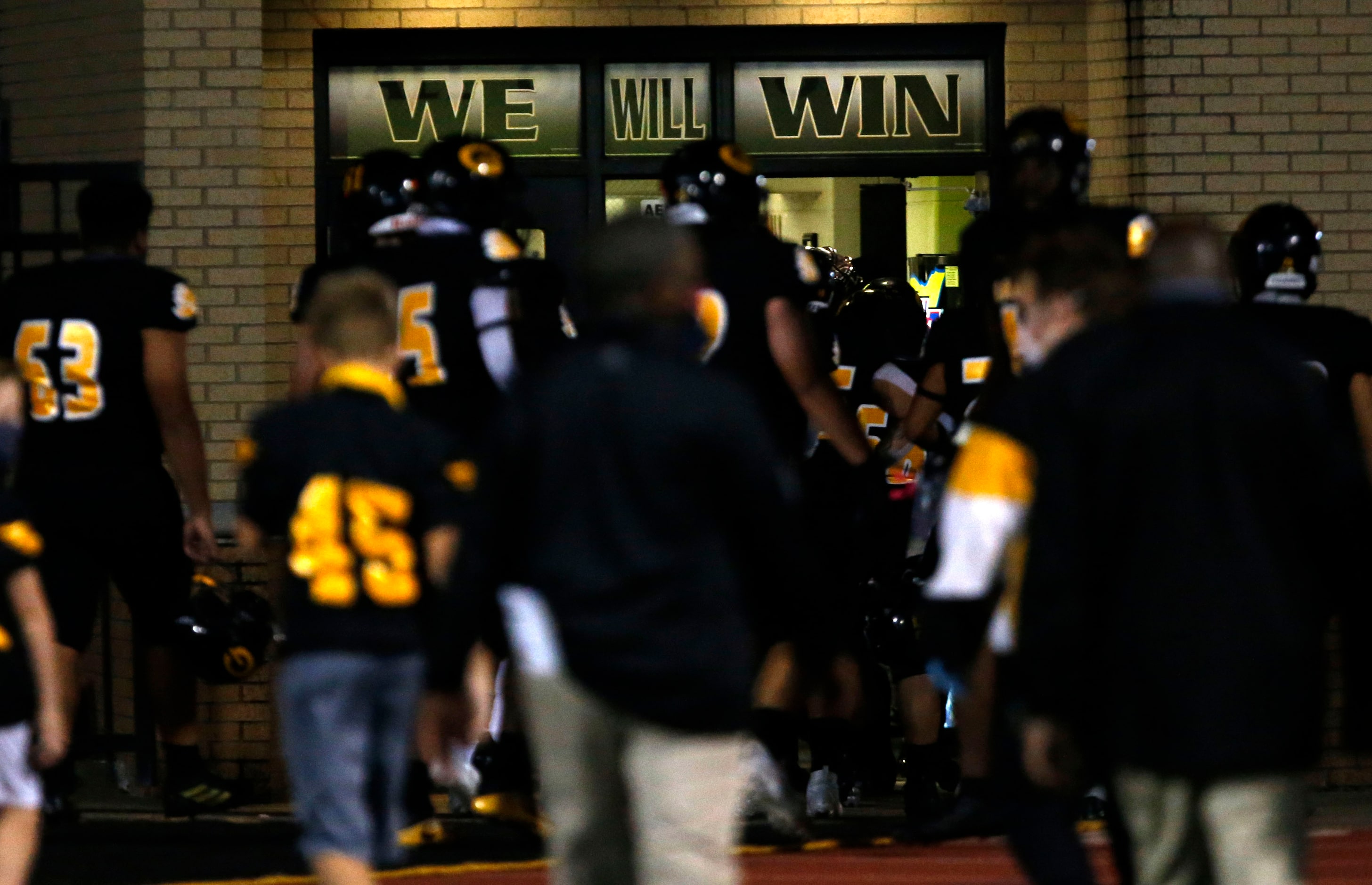 The Garland Owls head to the locker room during half-time, under a window that reads “WE...