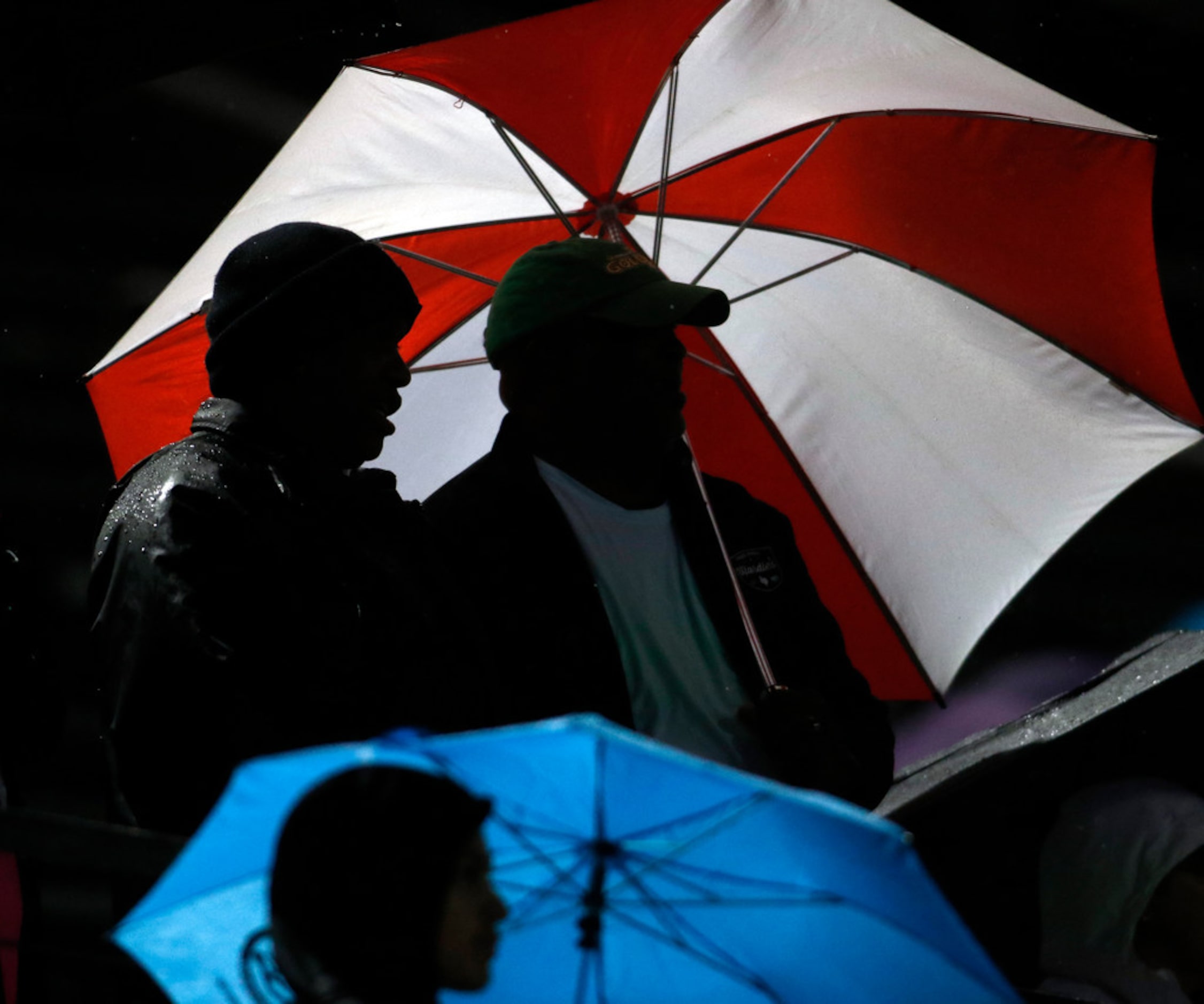 Mansfield Summit fans huddle under the cover of umbrellas during a rain-soaked first half...