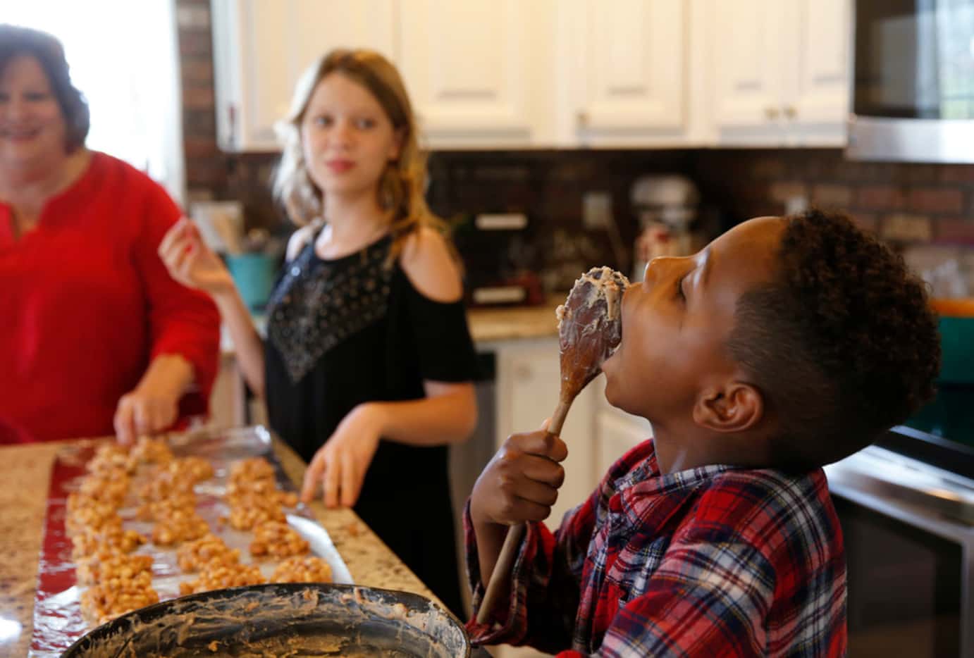 Josiah Reeves, 8, eats what's left on a spoon as Tena Gilbert (left) and Alyssa Reeves, 13...