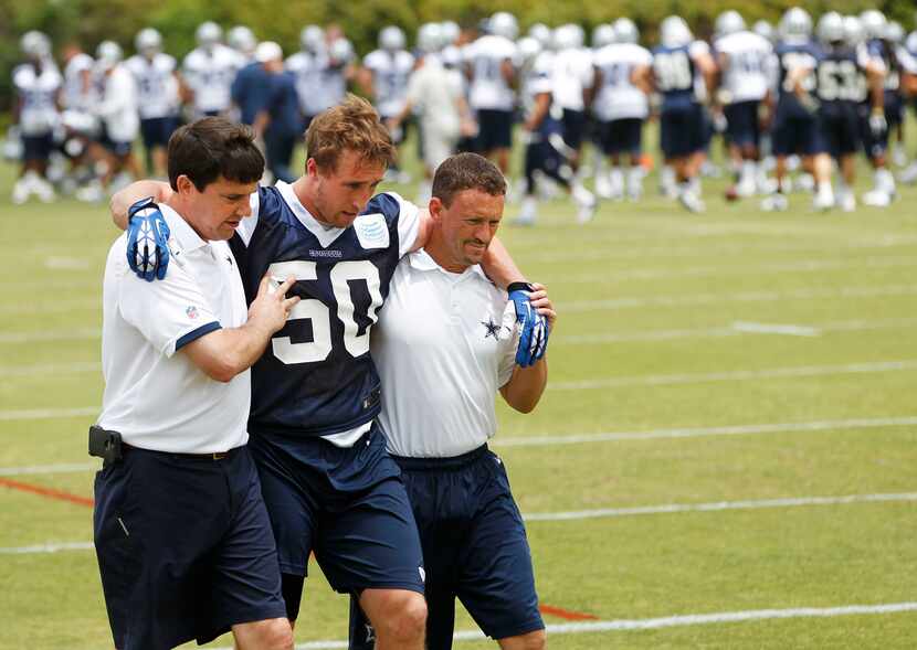 Dallas Cowboys Sean Lee is helped off the field by Dallas Cowboys head athletic trainer Jim...