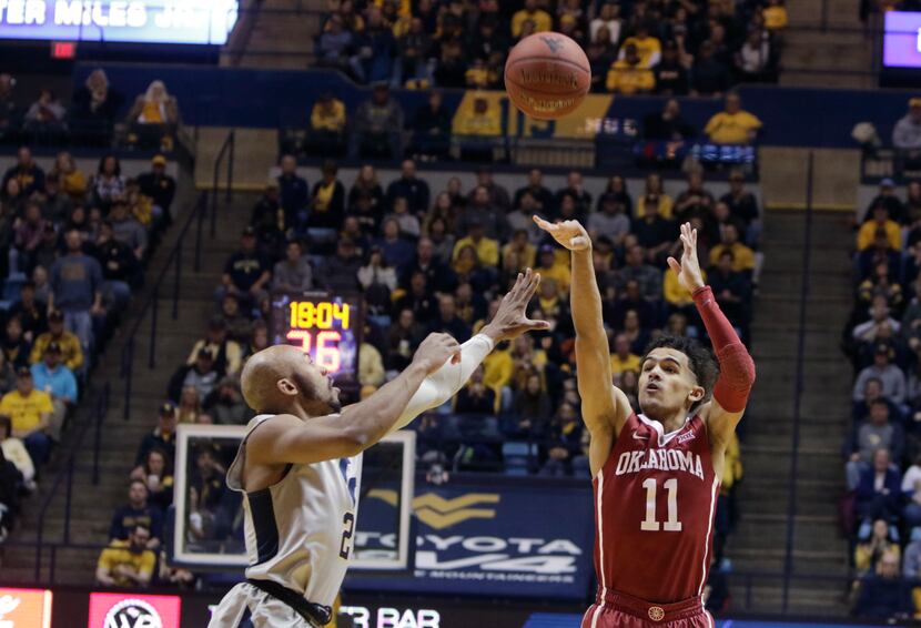 Oklahoma guard Trae Young (11) shoots while being defended by West Virginia guard Jevon...