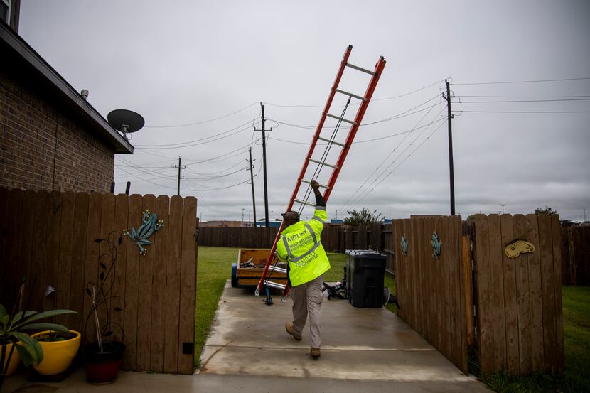 O’Neal Young, broadband installation technician for MB Link, carries a ladder as he works on...