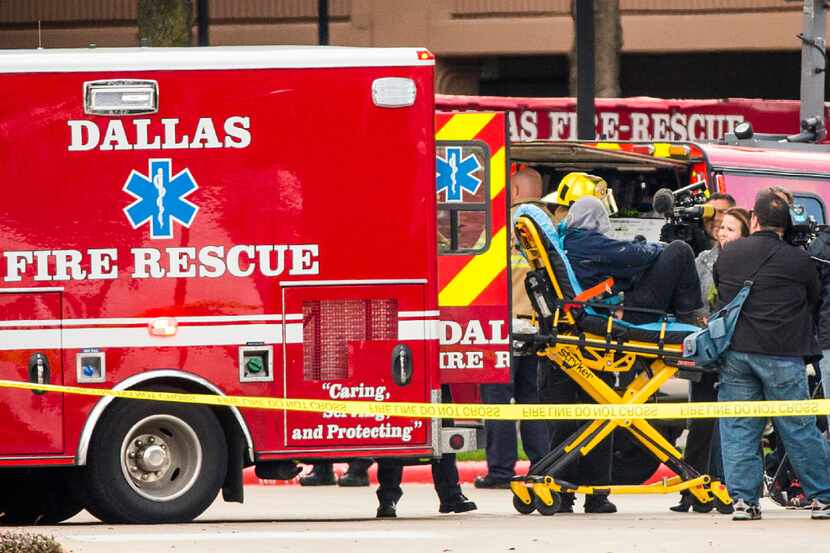 Dallas Fire Department paramedics aid a window washer who was rescued after being suspended...