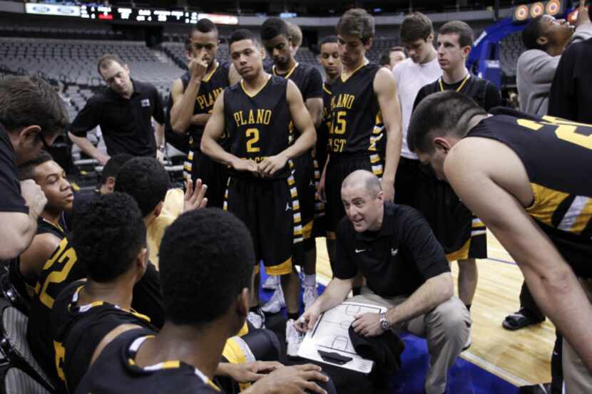 Plano East High School basketball coach Jeff Clackson talks with his players between...