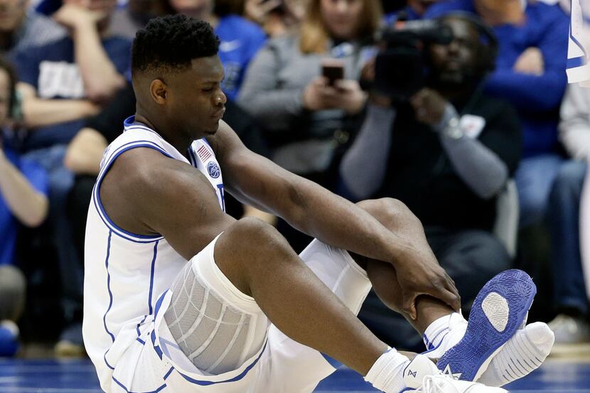 Duke's Zion Williamson sits on the floor following an injury during the first half of an...