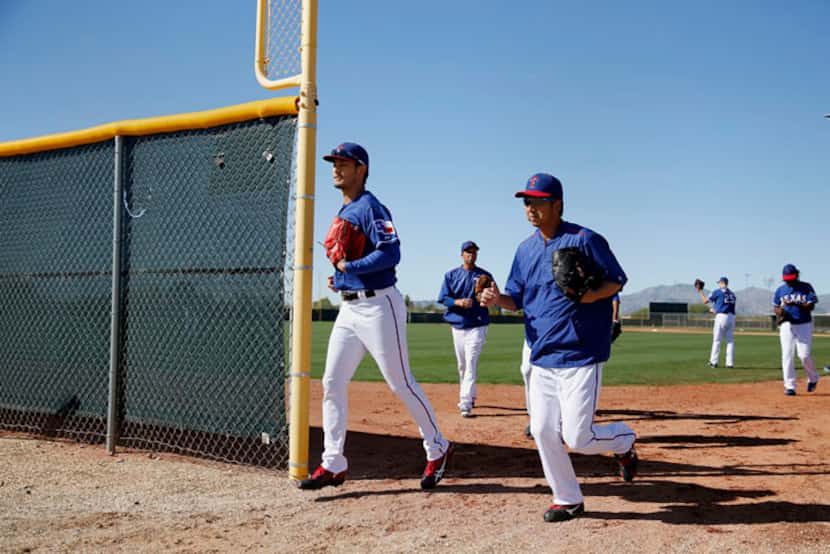  Texas Rangers pitcher Yu Darvish and Kyuji Fujikawa run to their assigned fields after...