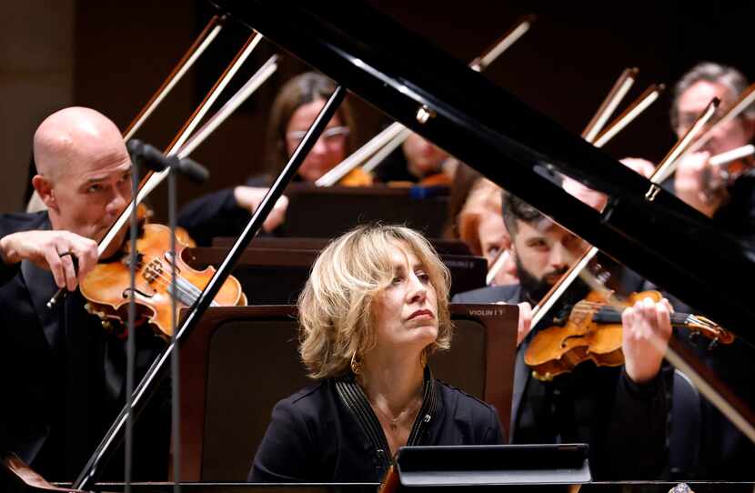 During a pause in her performance, pianist Ingrid Fliter watches as Edo de Waart guest...