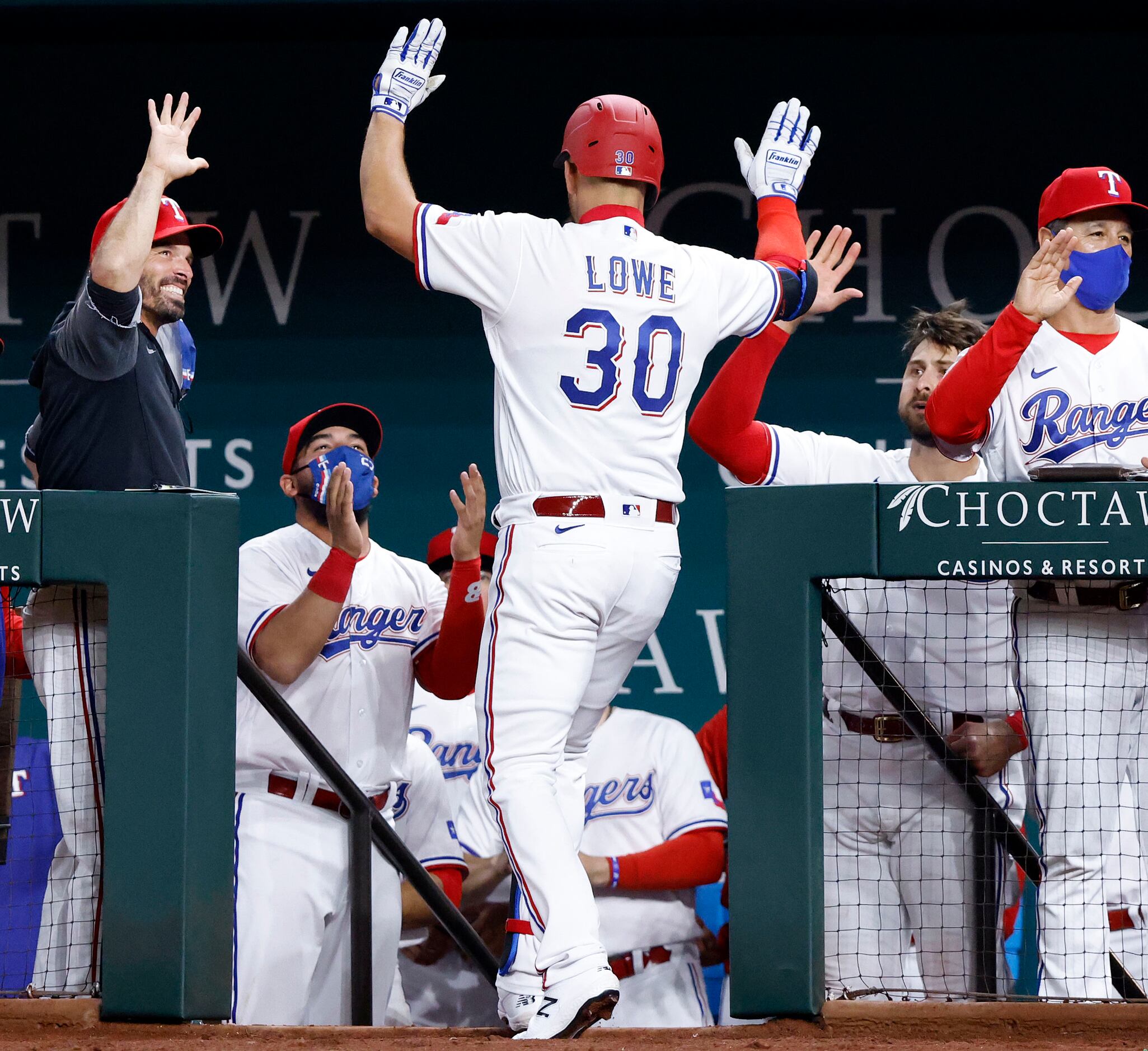 Texas Rangers batter Nate Lowe is congratulated by manager Chris Woodward (left) and...