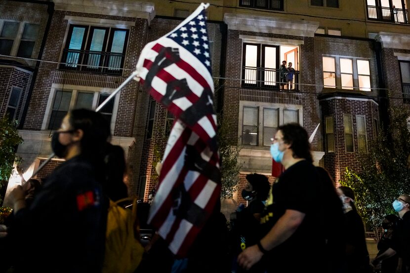 People watch from balcony as demonstrators march through Uptown on Wednesday, Sept. 23, 2020...