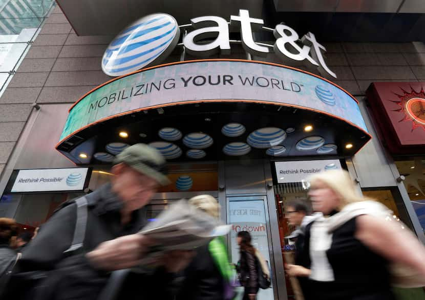 In this Oct. 21, 2014 photo, people pass an AT&T store in New York's Times Square. AT&T is...