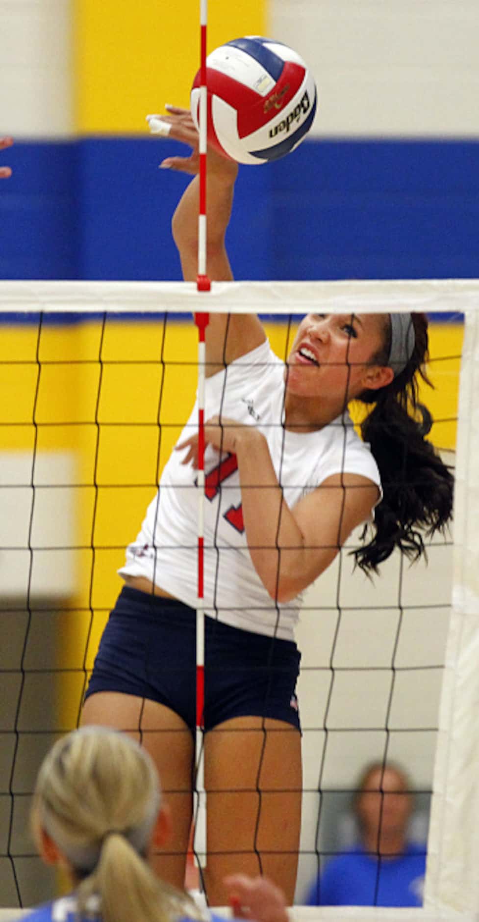 Frisco Centennial's Micaya White (11) spikes the volleyball over the net for a point against...