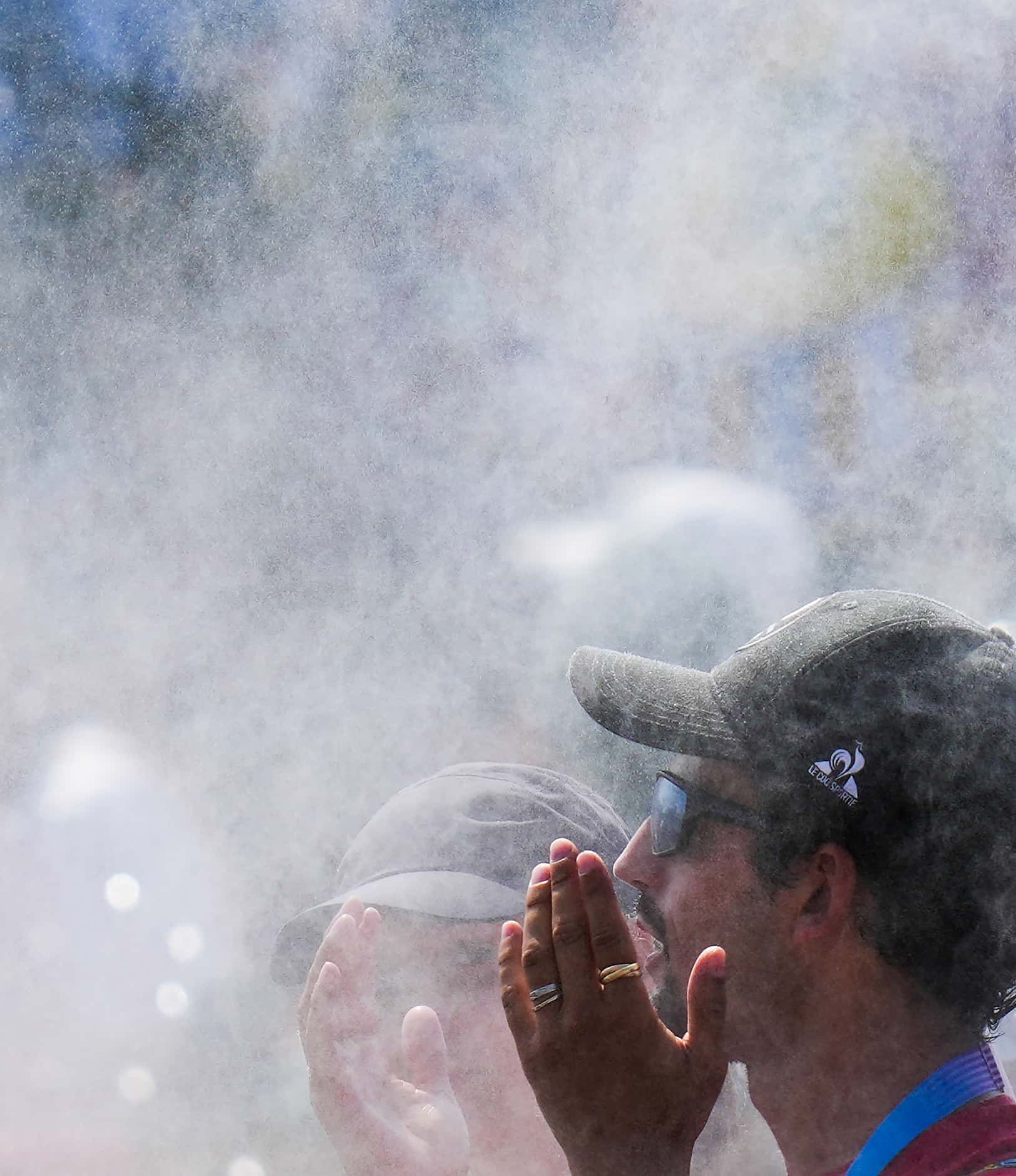 Spectators cool off under misting stations outside the 3x3 basketball venue at the 2024...