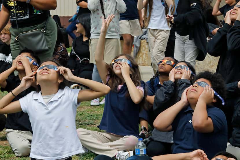 Luna Swedberg (center), 9, points to the eclipse as she views the eclipse with special...