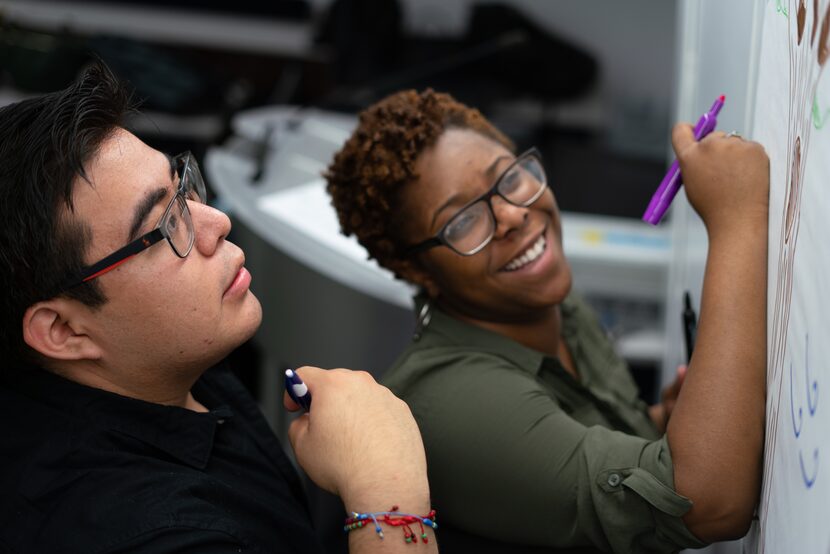 Two Year Up students work on a group assignment, one wears glasses and holds a purple pen.