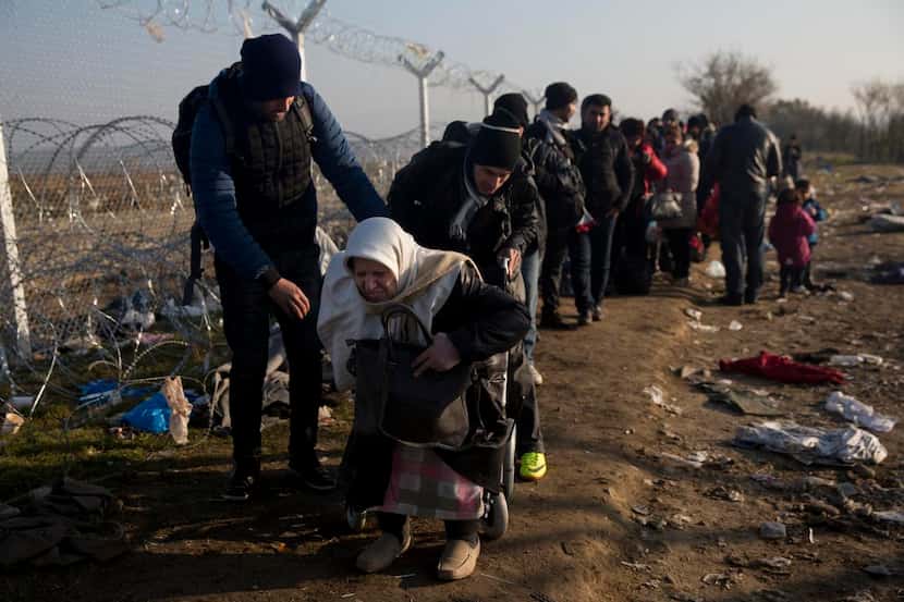 Una anciana siria recibe ayuda de su hijo para cruzar de Grecia a Macedonia. Grecia es el...