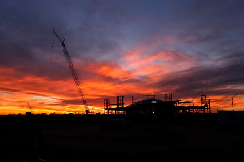 The sun sets behind AT&T Stadium and the Texas Live! construction site in Arlington.