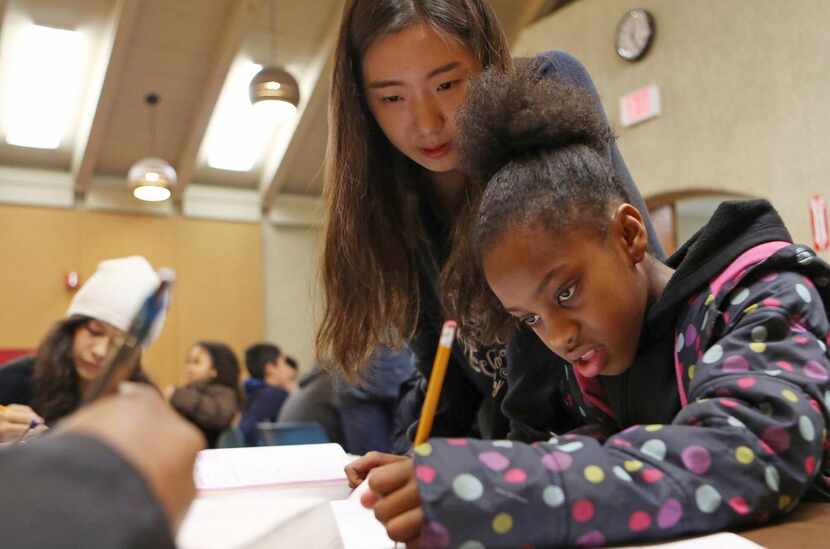 
Diana Pyun, a student tutor, works with Dejarae Thomas, 10, on fractions at Skyline Branch...