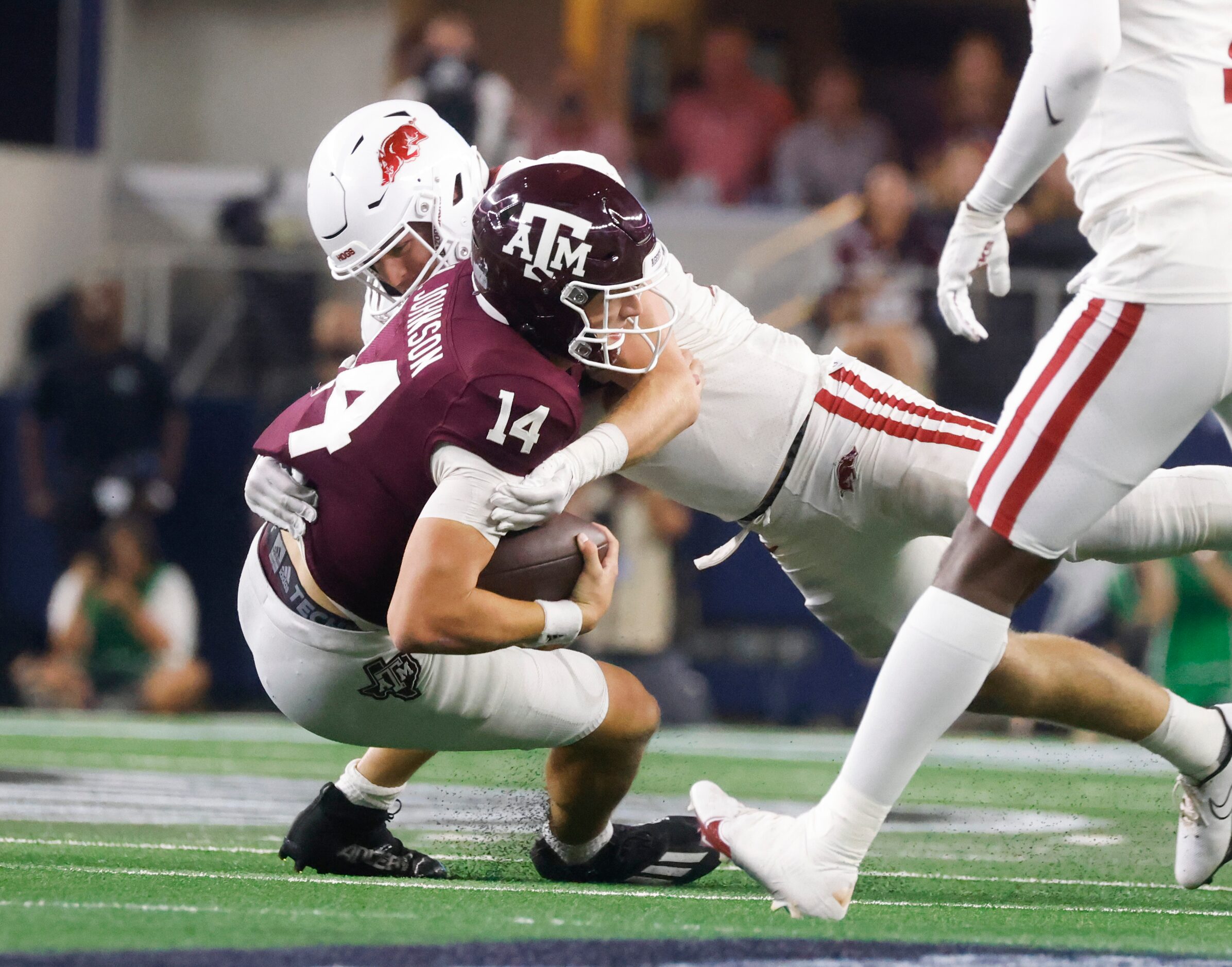 Texas A&M quarterback Max Johnson (14) gets tackled by Arkansas linebacker Bumper Pool (10)...