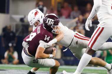 Texas A&M quarterback Max Johnson (14) gets tackled by Arkansas linebacker Bumper Pool (10)...