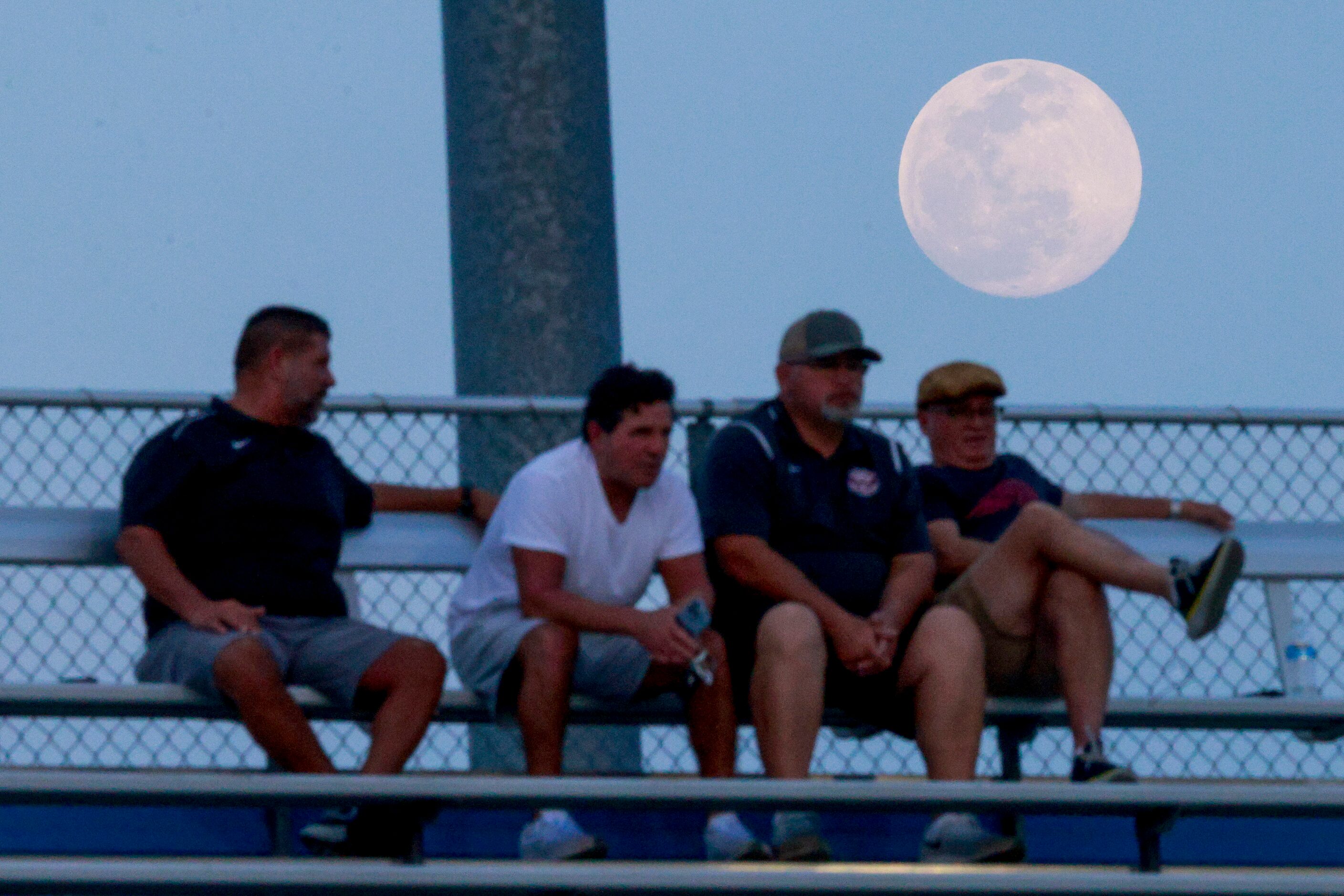 A nearly full moon rises over a group of fans during the first half of a Class 6A boys...