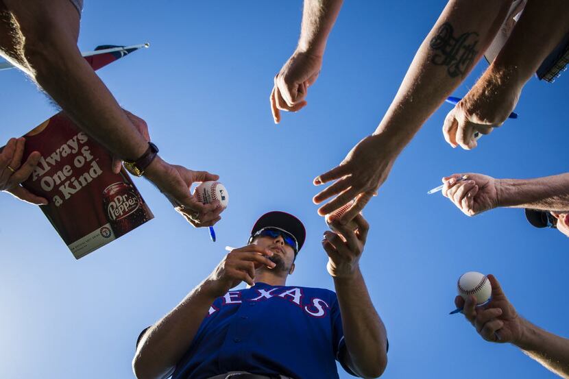 Texas Rangers pitcher Yu Darvish signs autographs for fans during a spring training workout...