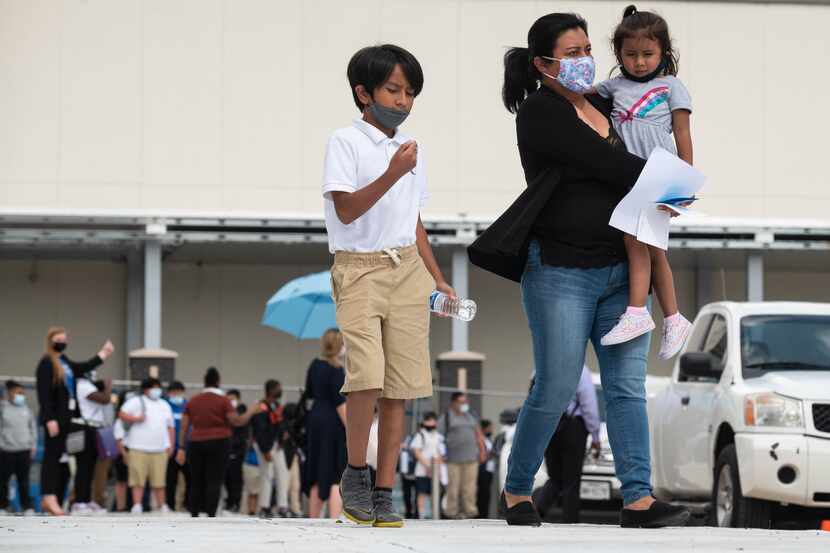A mother walks with her children after her son's first day back to school at E.D. Walker...