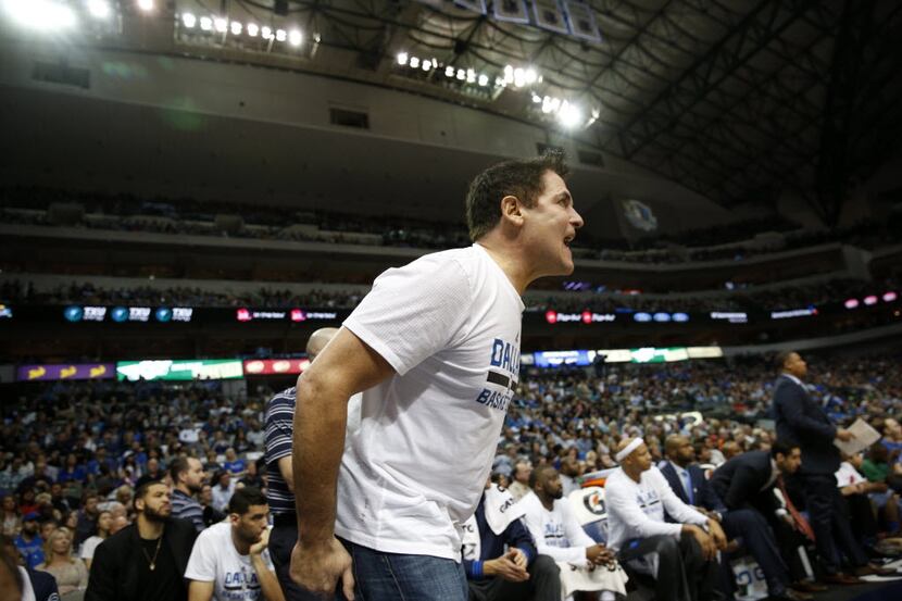 Dallas Mavericks owner Mark Cuban gets up out of his seat to yell for a traveling call...