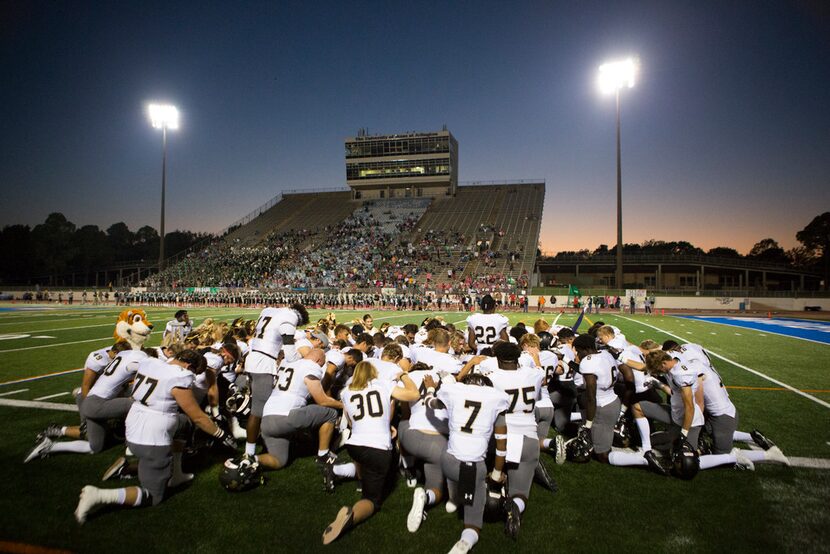 Mansfield players and cheerleaders pray before taking the field during a high school...