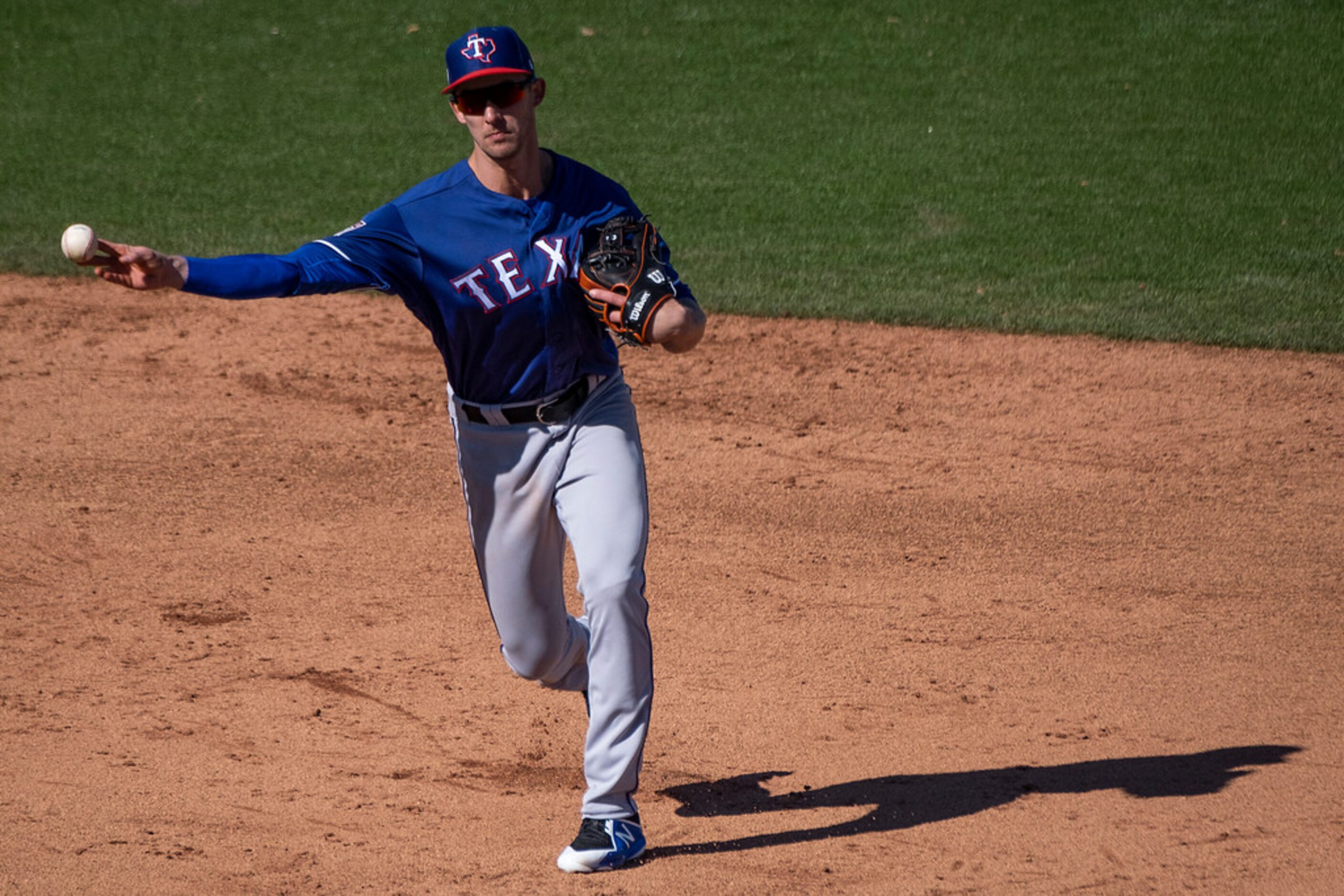 Texas Rangers shortstop Eli White makes a throw to first during a spring training baseball...