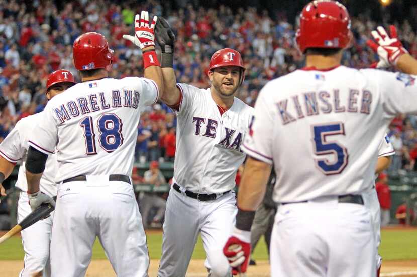 Texas catcher Mike Napoli is greeted by teammates Mitch Moreland (18) and Ian Kinsler (5)...
