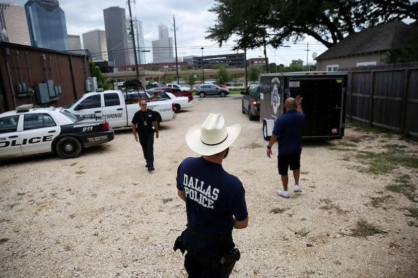 A Dallas police officer waits while a truck is backed in as members of the Dallas Police...