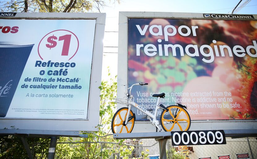 A VBike rental bike is left up on an elevated billboard along West Lawther Drive in Dallas...