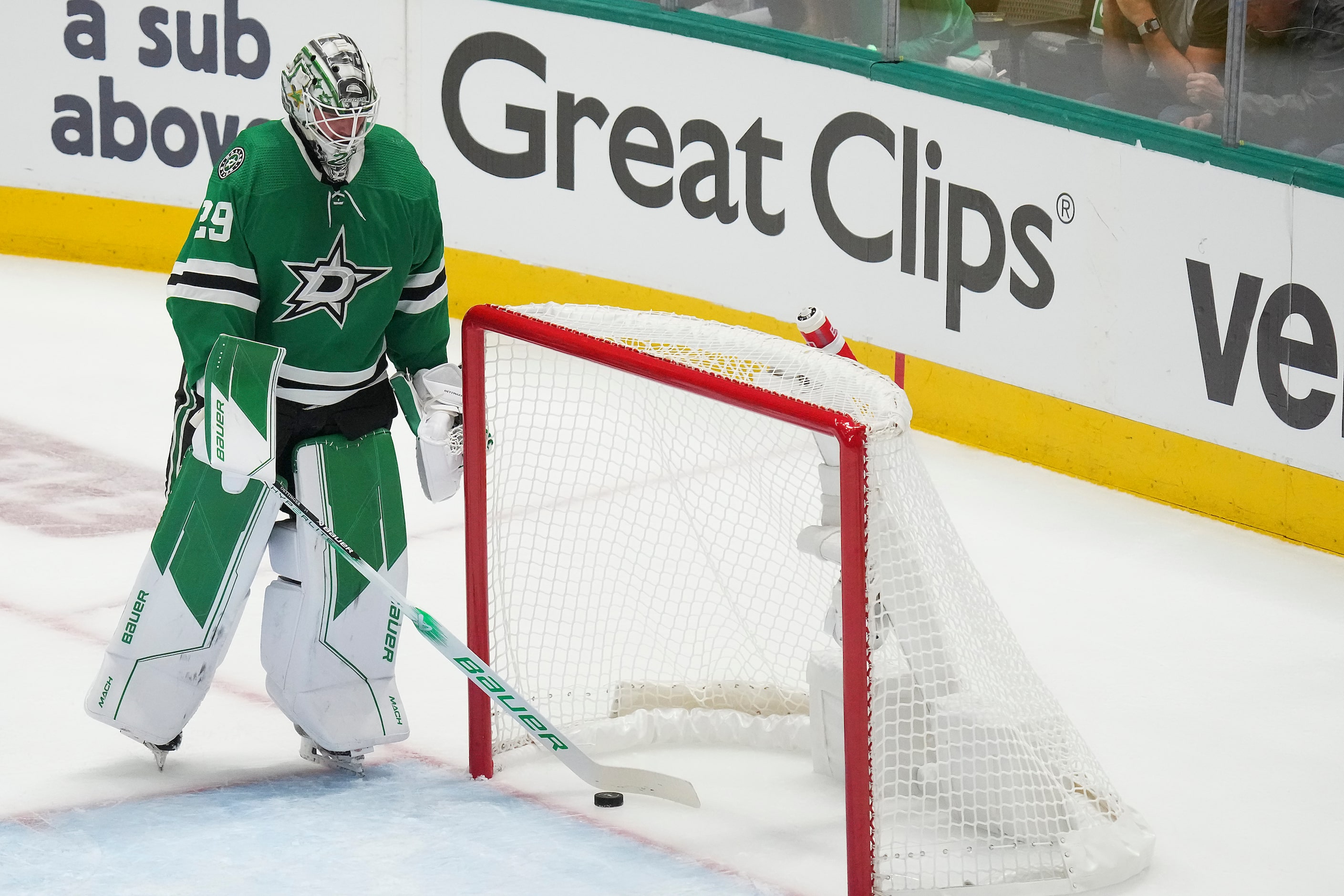 Dallas Stars goaltender Jake Oettinger sweeps the puck from the net after a goal by Vegas...