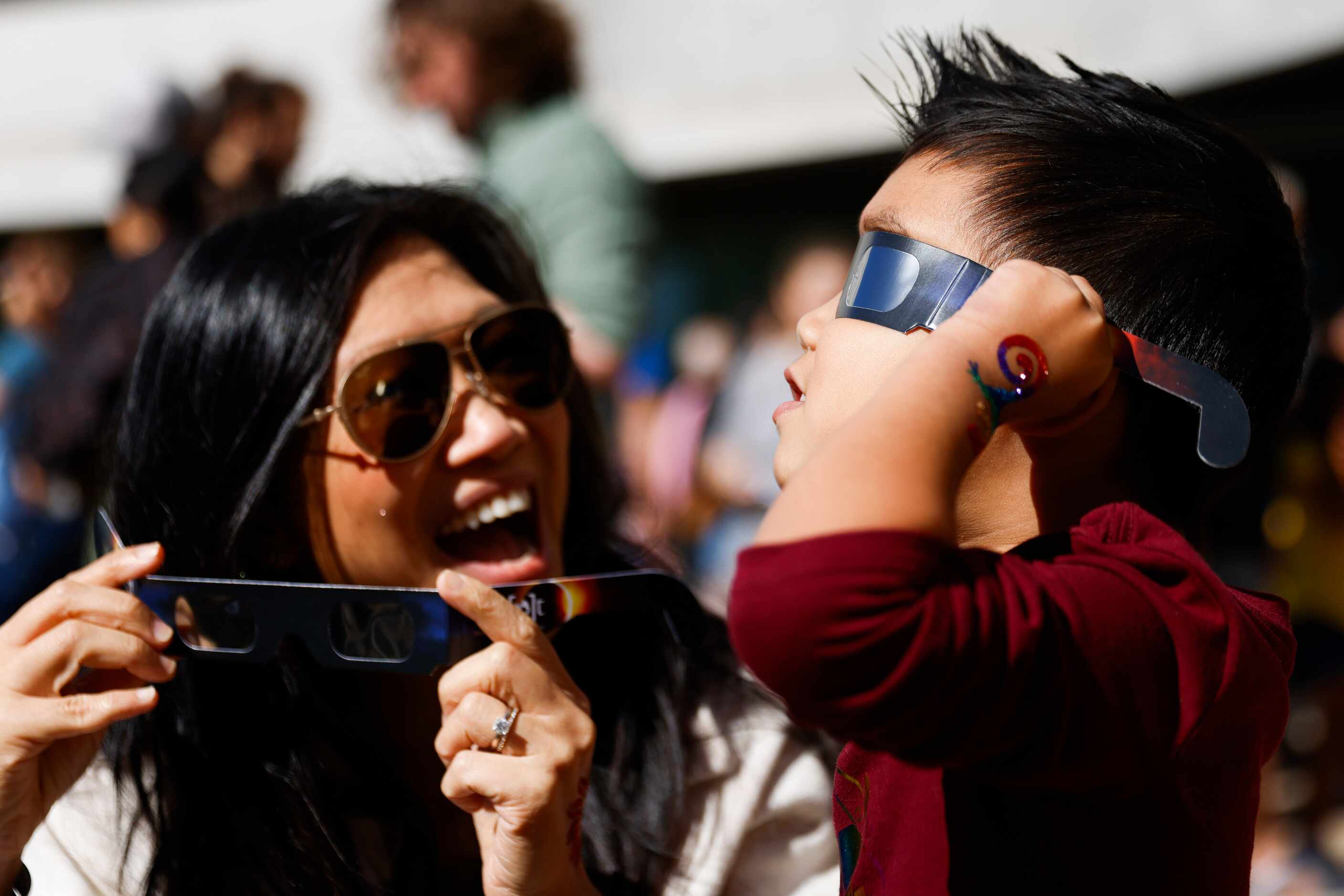 Sandy Ng reacts towards her son Jett, 3, as he takes a peek of the annular solar eclipse on...