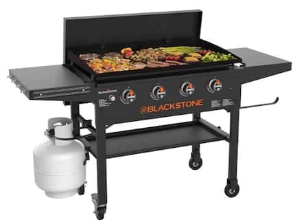 Stand-up griddle in black with variety of foods on the surface and a white propane tank on...
