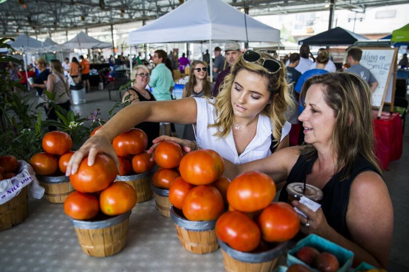 Shoppers at the Dallas Farmers Market check out tomatoes from the Lemley's Farms table.