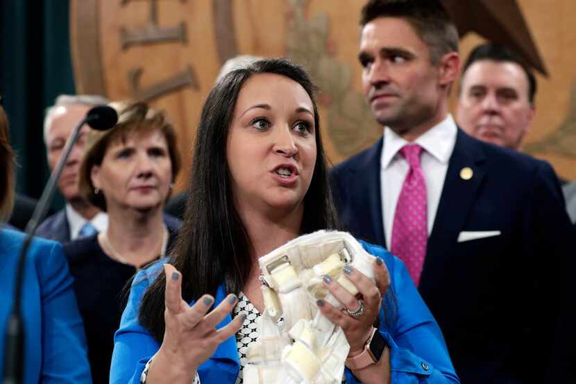 Claire Cullwell holds a brace she wore as a newborn as she stands with Texas lawmakers and...