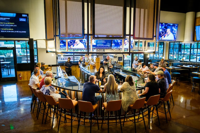 Televisions surround a bar at Sidecar Social, a new two-story "interactive social lounge" in...