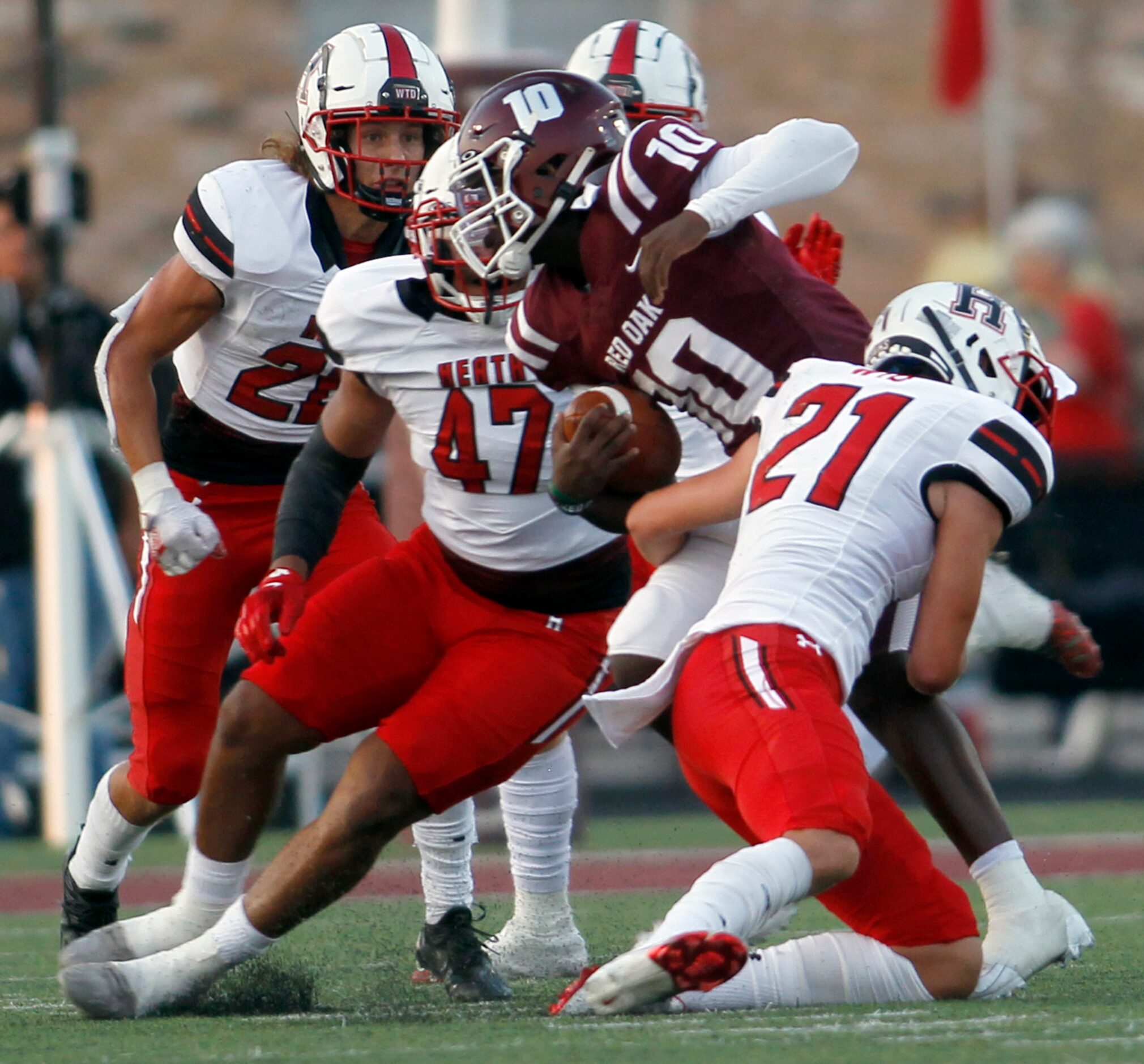 Red Oak quarterback Jaylon Robinson (10) attracts a crowd of Rockwall Heath defenders...