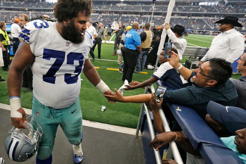 Dallas Cowboys center Joe Looney (73) greets a fan as he leaves the field after the game...