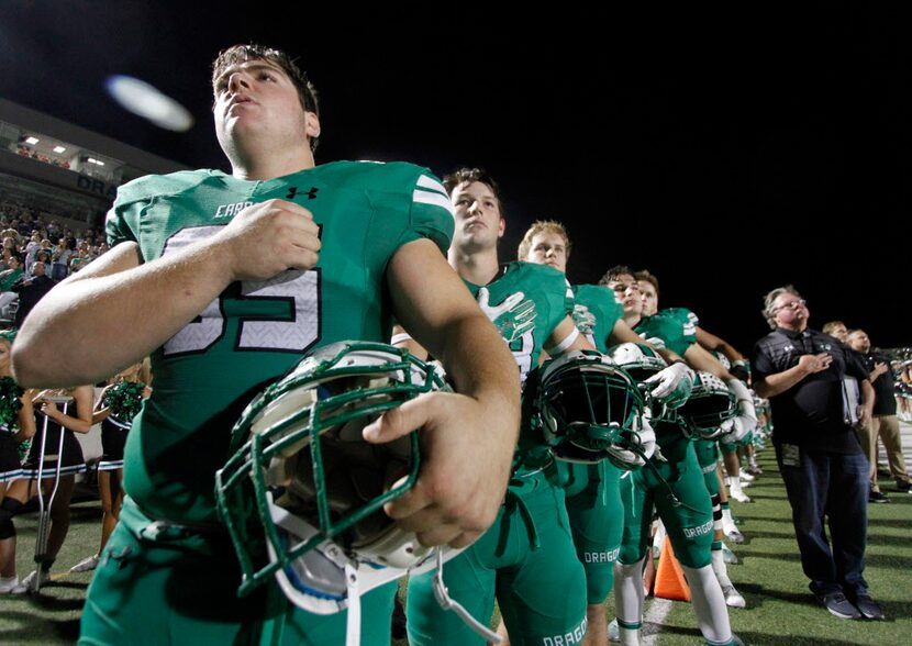 Members of the Southlake Carroll Dragons pause for the playing of the national anthem prior...