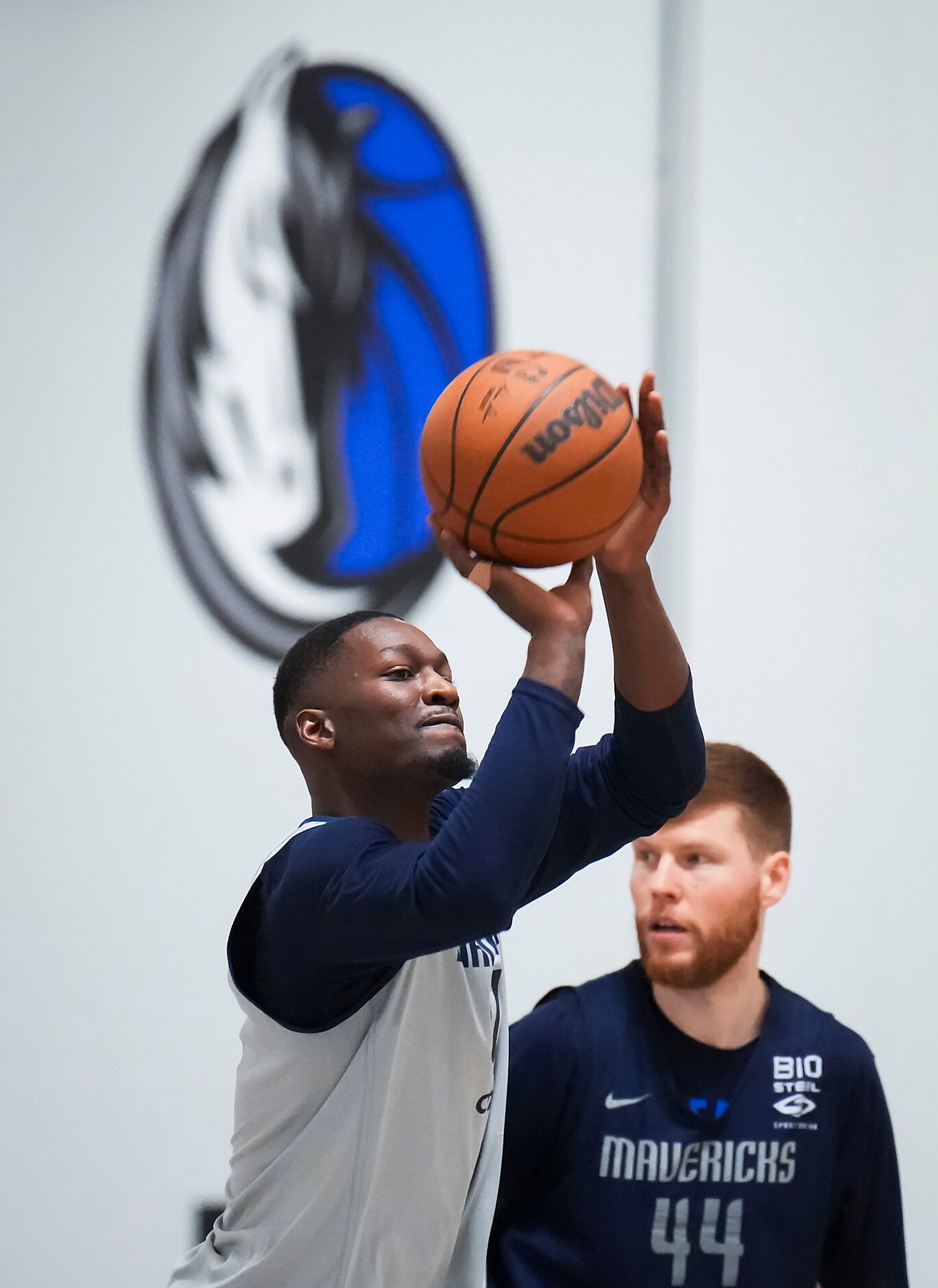 Dallas Mavericks forward Dorian Finney-Smith shoots while forward Davis Bertans looks on as...