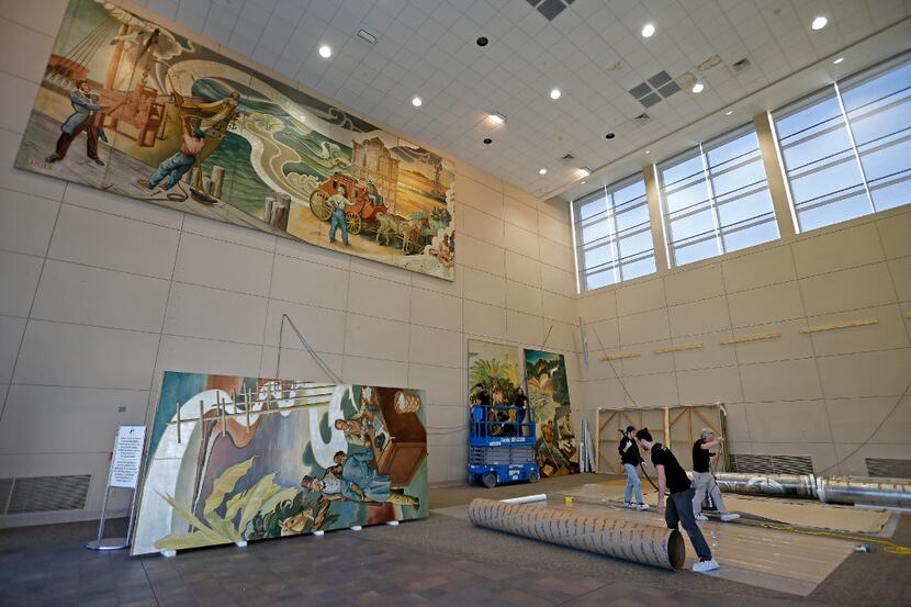 Workers from Unified Fine Arts work to remove the murals from the wall of the TXCN building ...