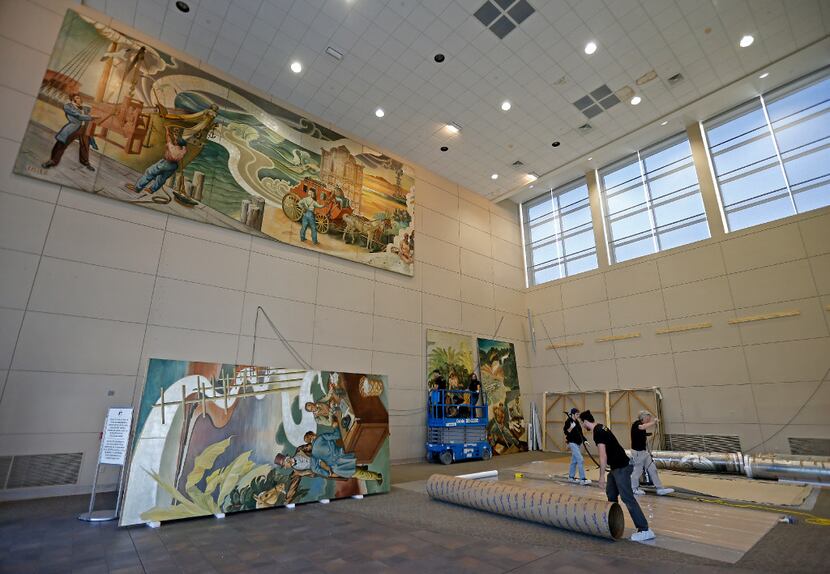 Workers from Unified Fine Arts work to remove the murals from the wall of the TXCN building ...