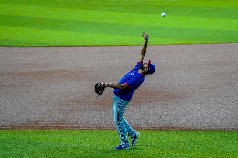 Texas Rangers infielder Isiah Kiner-Falefa tosses a ball in the infield during the Rangers...
