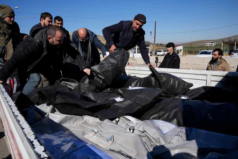 Hombres cargando cuerpos de víctimas sirias para su traslado a Siria en la localidad de...