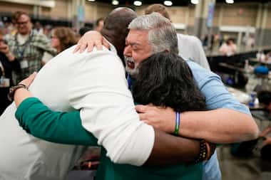 David Meredith (center) hugs fellow observers after an approval vote at the United Methodist...