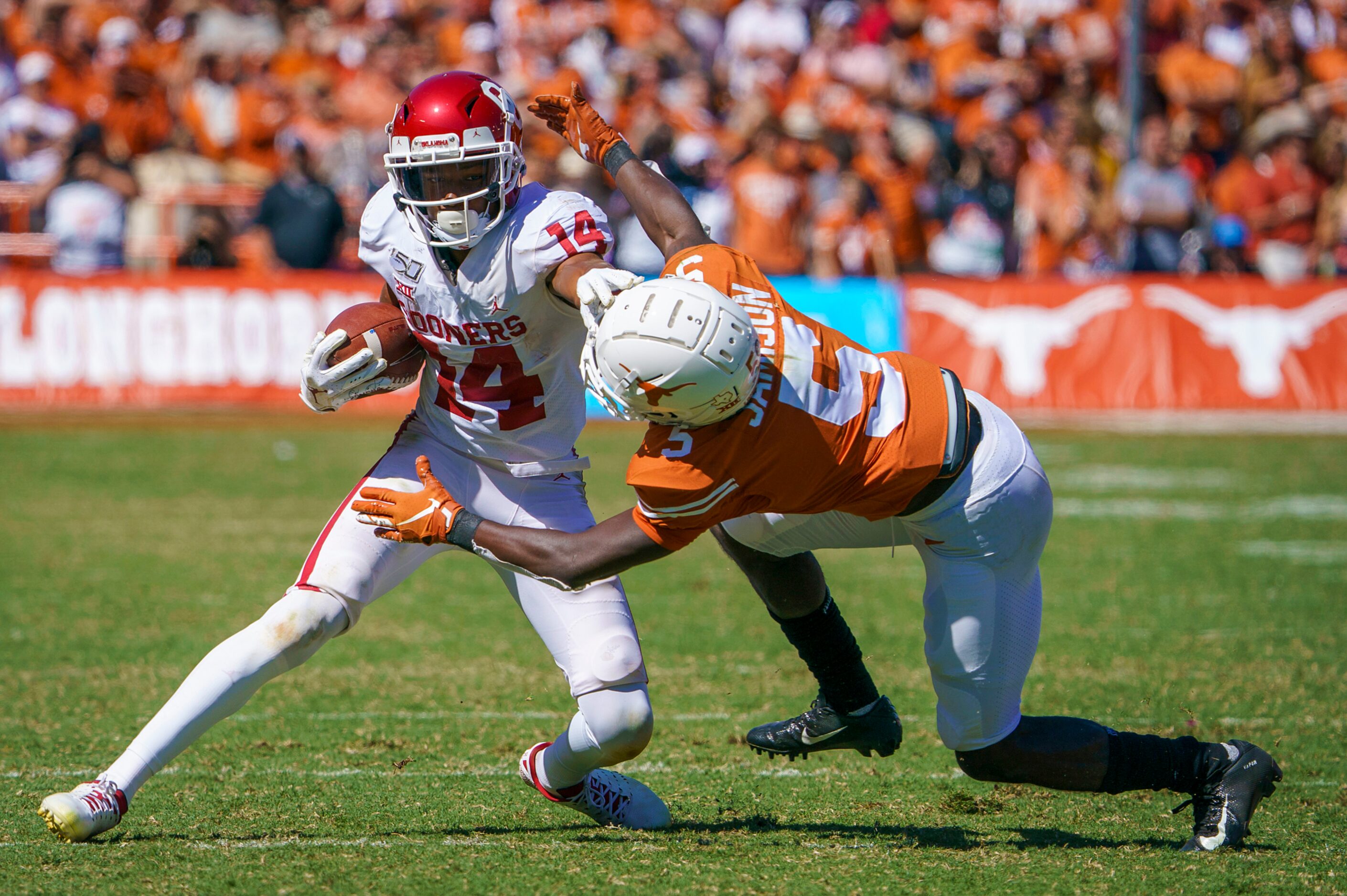 Oklahoma wide receiver Charleston Rambo (14) pushes off of Texas defensive back D'Shawn...