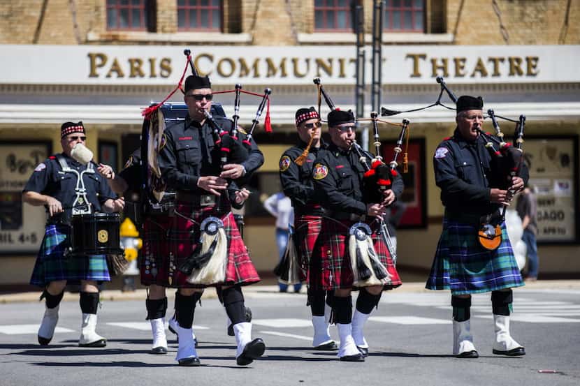 The Plano Firefighters Pipes & Drums Corps lead fire trucks down 1st Street during a Monday,...